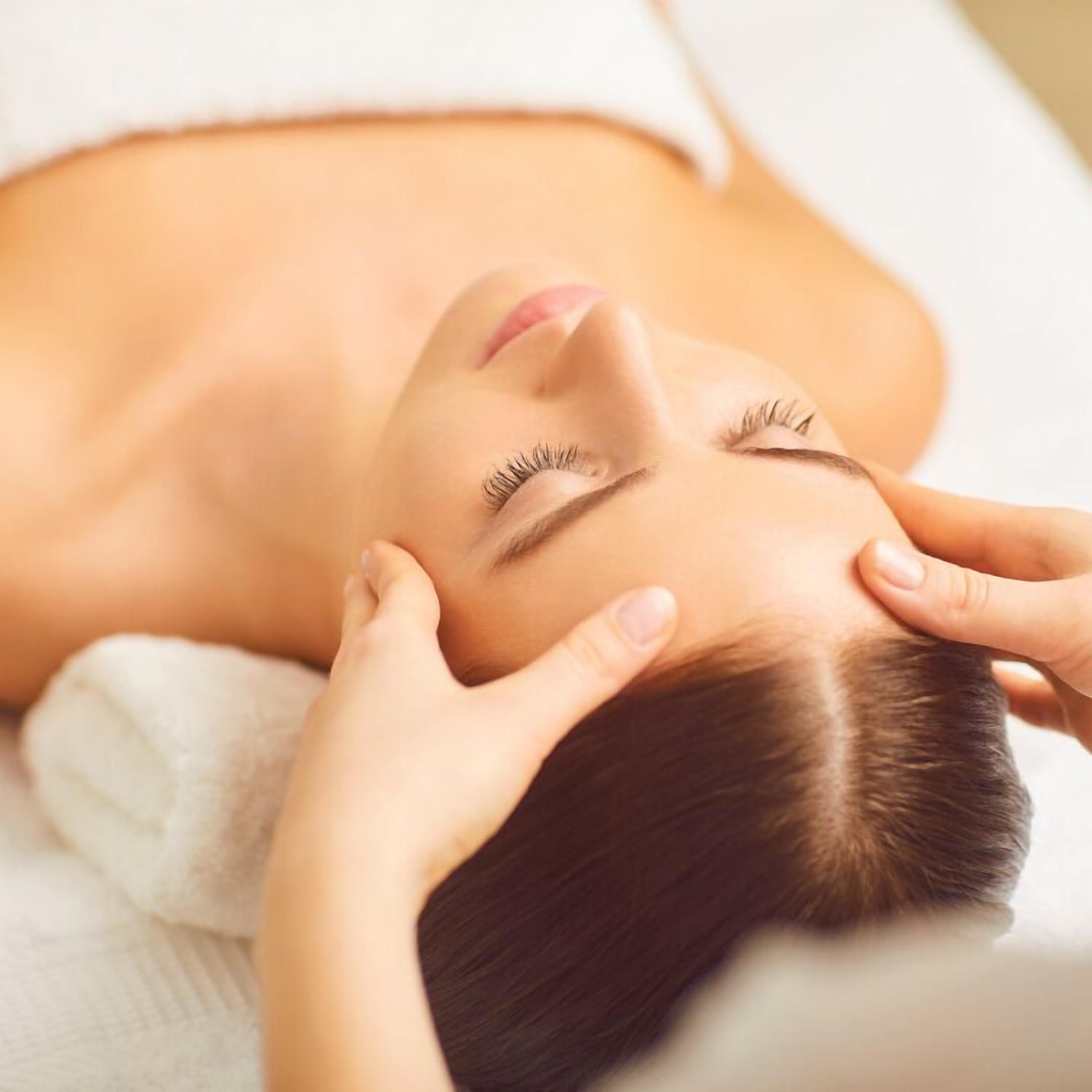 A person lying down with hands on their head, possibly receiving a massage.