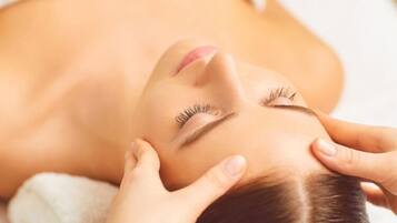 A person lying down with hands on their head, possibly receiving a massage.
