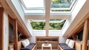 A cozy room with a sloped ceiling, skylights, a bed, two seating areas, and a small table. - Domaine du Val Sauvage (Langeais)