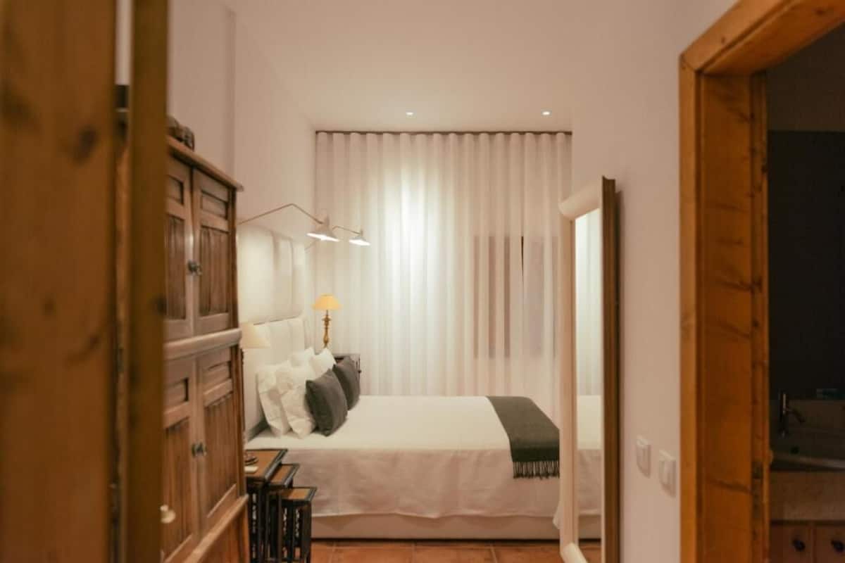A bedroom with a bed, a nightstand, a lamp, and a wardrobe.