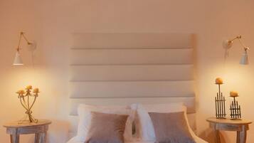 Quarto com uma cama grande, duas mesas de cabeceira e luminárias fixadas na parede.