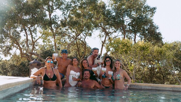 Un grupo de personas en una piscina con árboles al fondo.