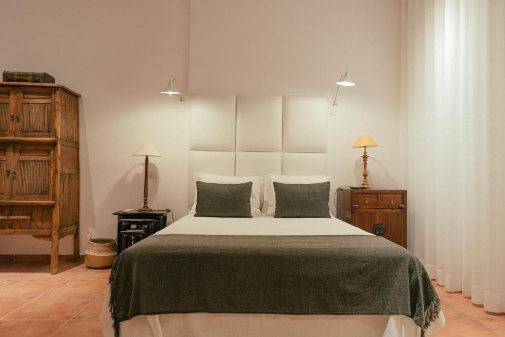 A bedroom with a bed, two bedside tables, a wooden cabinet, and a lamp.