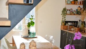 Un comedor con una mesa de madera, sillas y un ventanal con plantas.