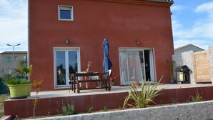 Un edificio rojo con un patio, una mesa con sillas y una planta en maceta.
