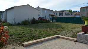 Un barrio residencial con casas, un patio cercado y un coche rojo estacionado al frente.