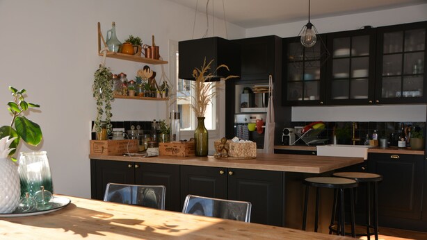 Una cocina moderna con armarios oscuros, encimera de madera y taburetes de bar.