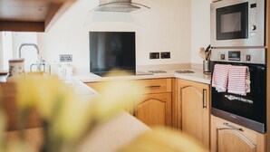 A modern kitchen with wooden cabinets, stainless steel appliances, and a glass range hood. - Cottage - Sleeps 4 - Garden - Parking (Llanelli)