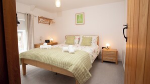 A bedroom with a bed, bedside tables, a hanging light fixture, and a framed quote on the wall. - Cottage - Sleeps 4 - Garden - Parking (Llanelli)