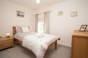 A bedroom with a bed, bedside table, and a dresser. - Cottage - Sleeps 4 - Garden - Parking (Llanelli)