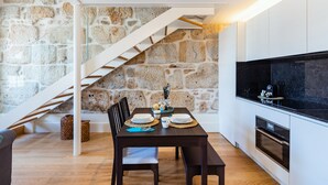 Eine moderne Küche mit einer Steinwand, einem Holzespeisetisch für vier Personen und einem eingebauten Backofen.