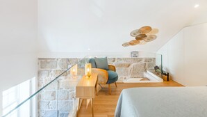 Ein modernes Zimmer mit Schreibtisch aus Holz, Weidenkorbstuhl und einer Steinwand.