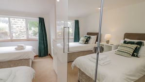 A hotel room with two beds, a mirror, a nightstand, and a window with curtains. - Bwthyn Pengwern (Caernarfon)