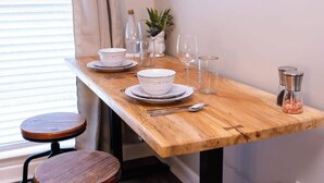 A wooden dining table set with white plates, bowls, and cutlery, accompanied by wine glasses and a small plant. - Skip the hotel. Stay 4 min from Maxwell, walk to downtown & Civil Rights landmarks, and bring your dog. (Montgomery)