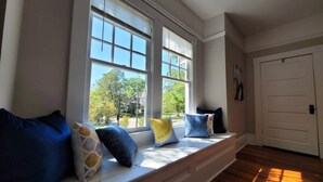 A room with a built-in bench along a window with blinds, a door, and a view of trees outside. - Made for the trips that bring everyone together. This historic Montgomery home gives families, wedding parties, and groups room to gather, room to disappear for a while, and one place to come back to—all minutes from downtown, Maxwell AFB, and the re (Montgomery)