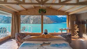 Een kamer met een bed, uitzicht op een meer en een berg op de achtergrond.