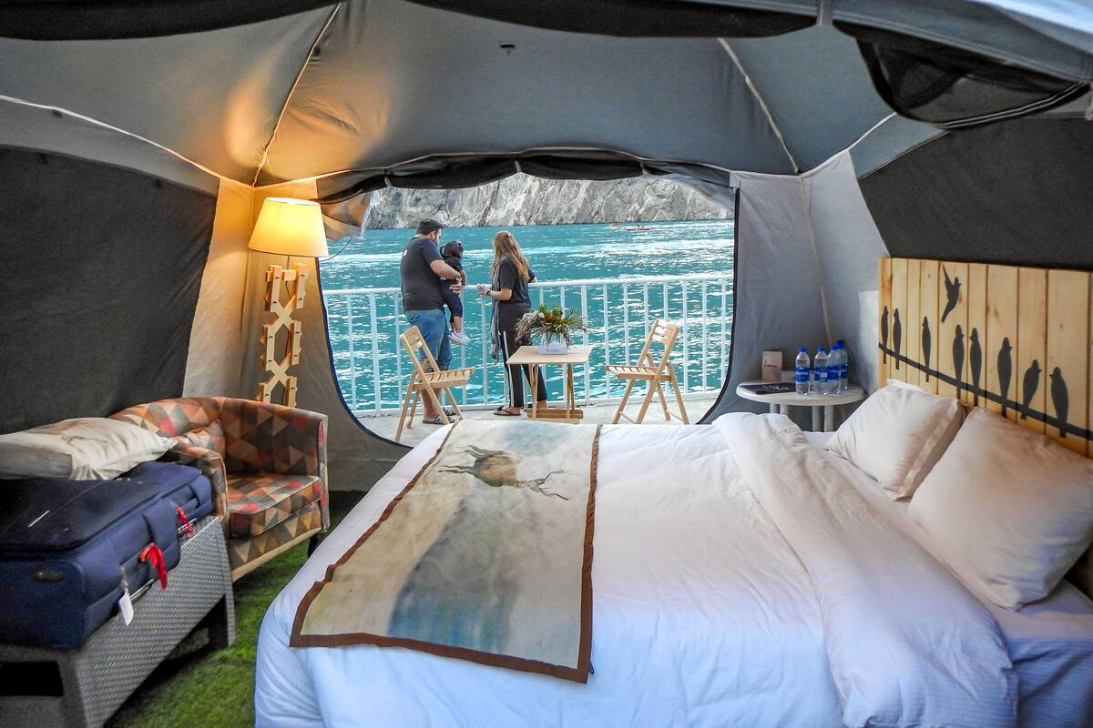 Alojamiento con tienda de campaña, cama, zona de estar y vistas al mar.