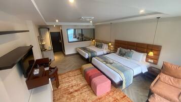 A hotel room with two beds, a desk, a chair, a small table, and a mirror.