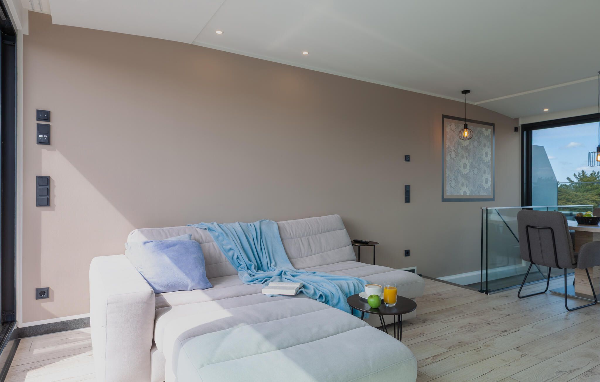 A modern living room with a sofa, a coffee table, and a dining area with a chair.