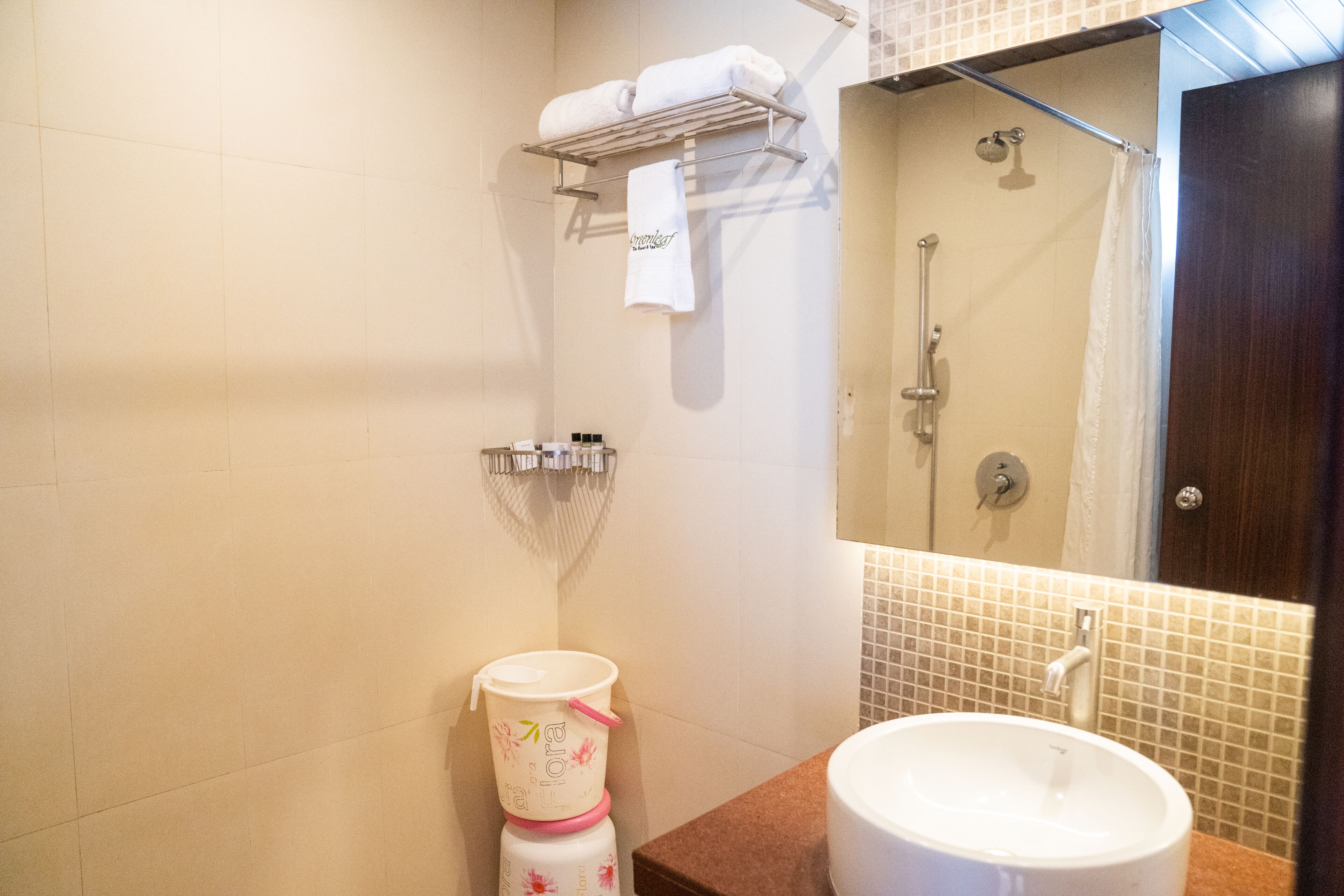 Een badkamer met een wastafel, spiegel, douche en handdoekhouder.