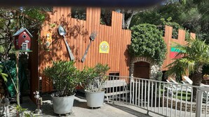 A courtyard with a wooden fence, potted plants, a birdhouse, and a sign with a logo. - Villa rental in APT (Apt)