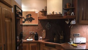 A kitchen with wooden cabinets, a map, a coffee maker, and a toaster. - Villa rental in APT (Apt)