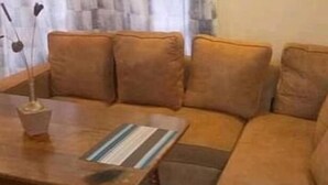 A living room with a brown sofa, a wooden coffee table, and a vase with a plant. - Stay.Plus Villa Serene Hotel Kitale (Kitale)