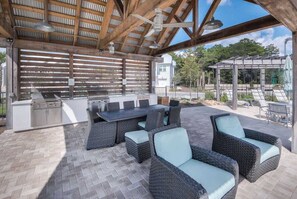 An outdoor patio with a grill, seating, and a pergola.