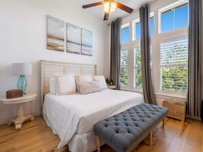 A bedroom with a bed, a bench, a nightstand, a lamp, and a ceiling fan.