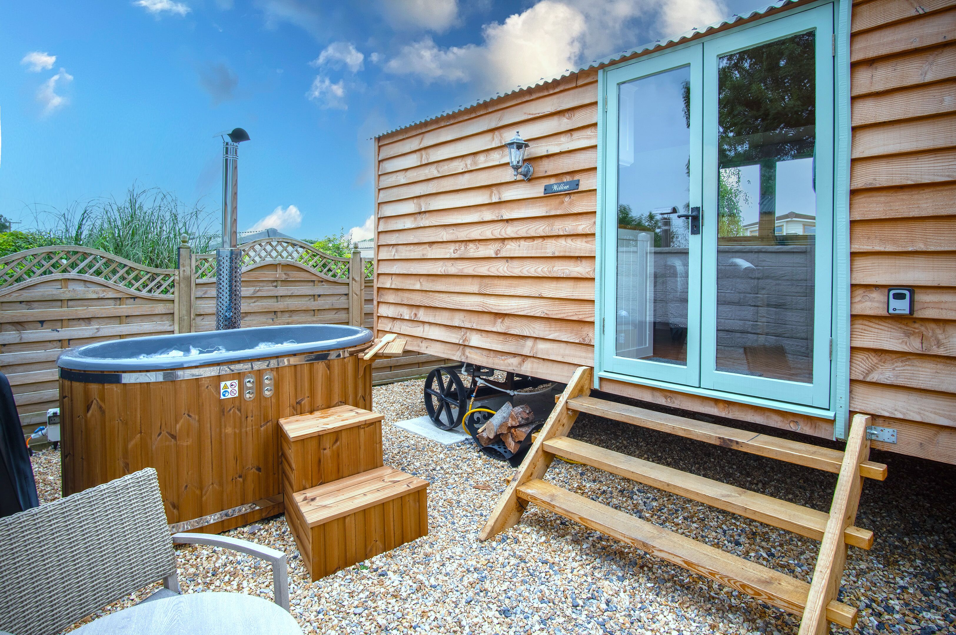 A wooden cabin with a hot tub, outdoor seating, and a covered area.