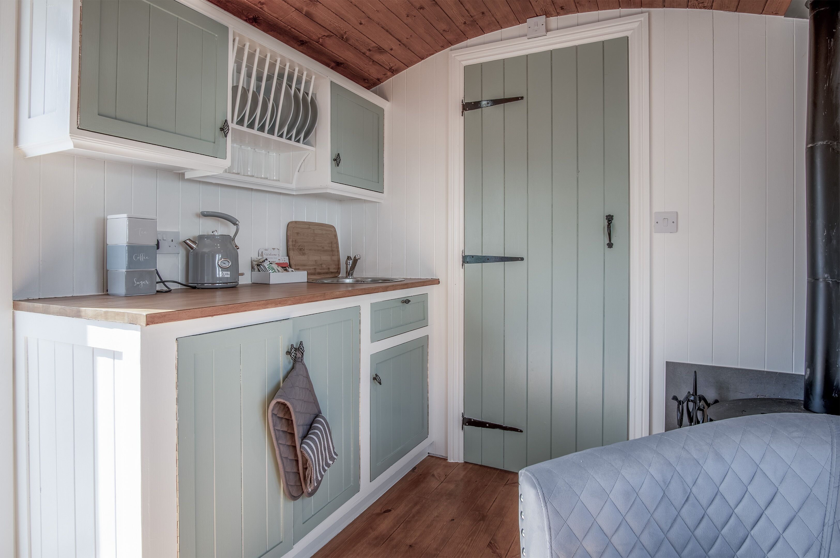 A compact kitchen with a coffee maker, a cutting board, and a hanging towel.