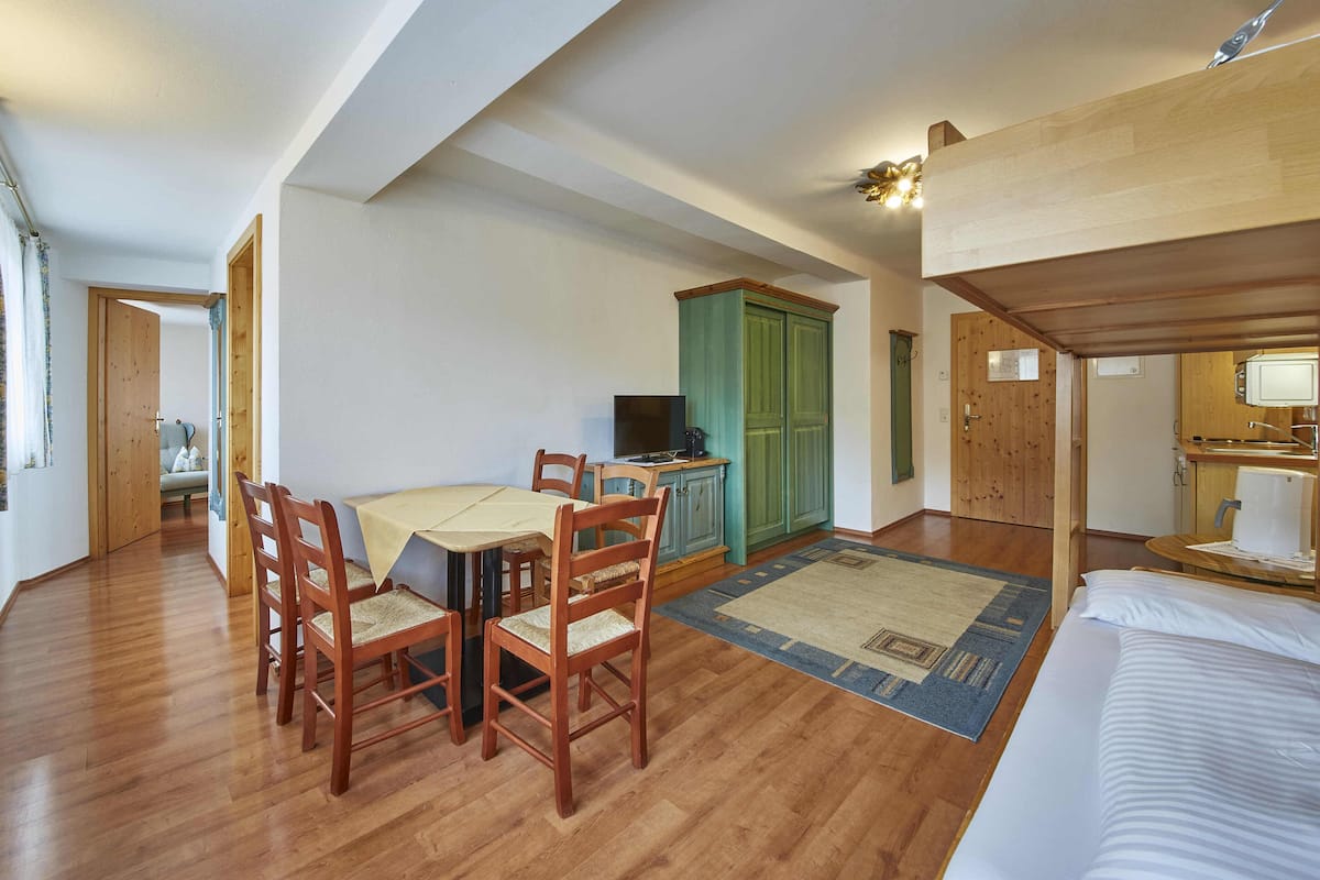 Une pièce chaleureuse avec une table à manger en bois, des chaises, un téléviseur et une armoire verte.
