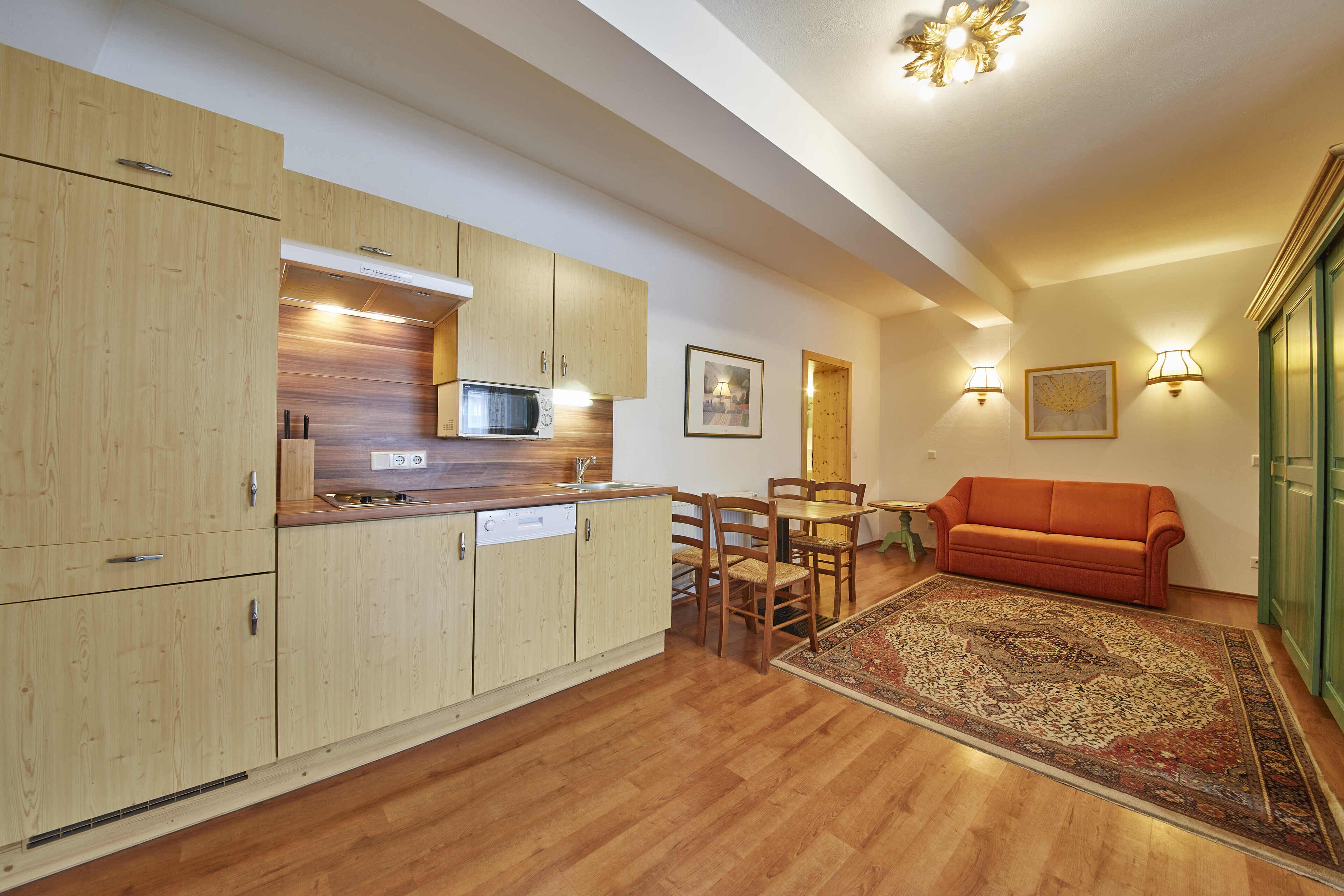 A modern kitchen with wooden cabinets, a microwave, and a dining area with a table and chairs.