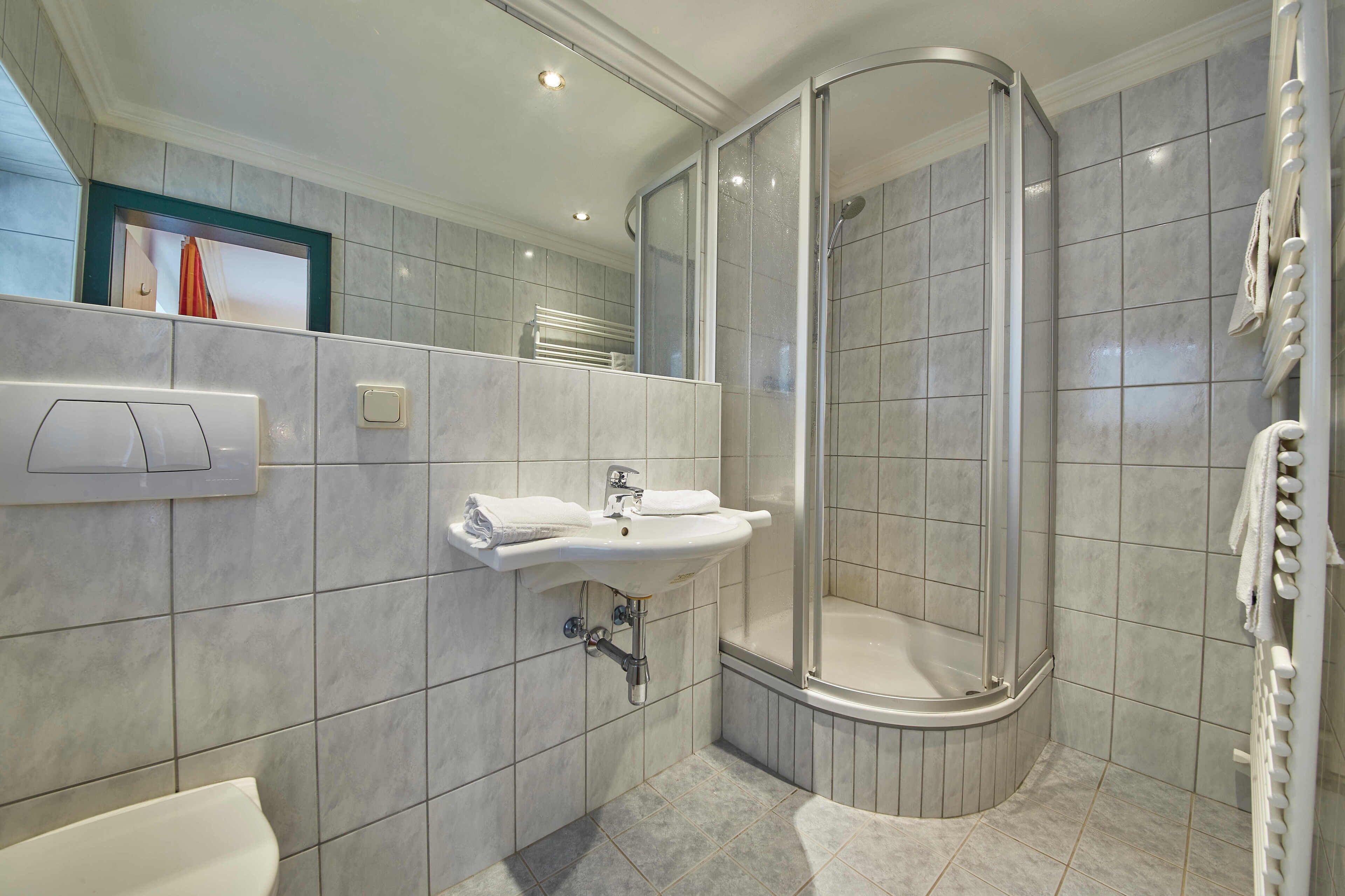 Une salle de bain moderne avec une douche à porte incurvée, un lavabo et des toilettes.