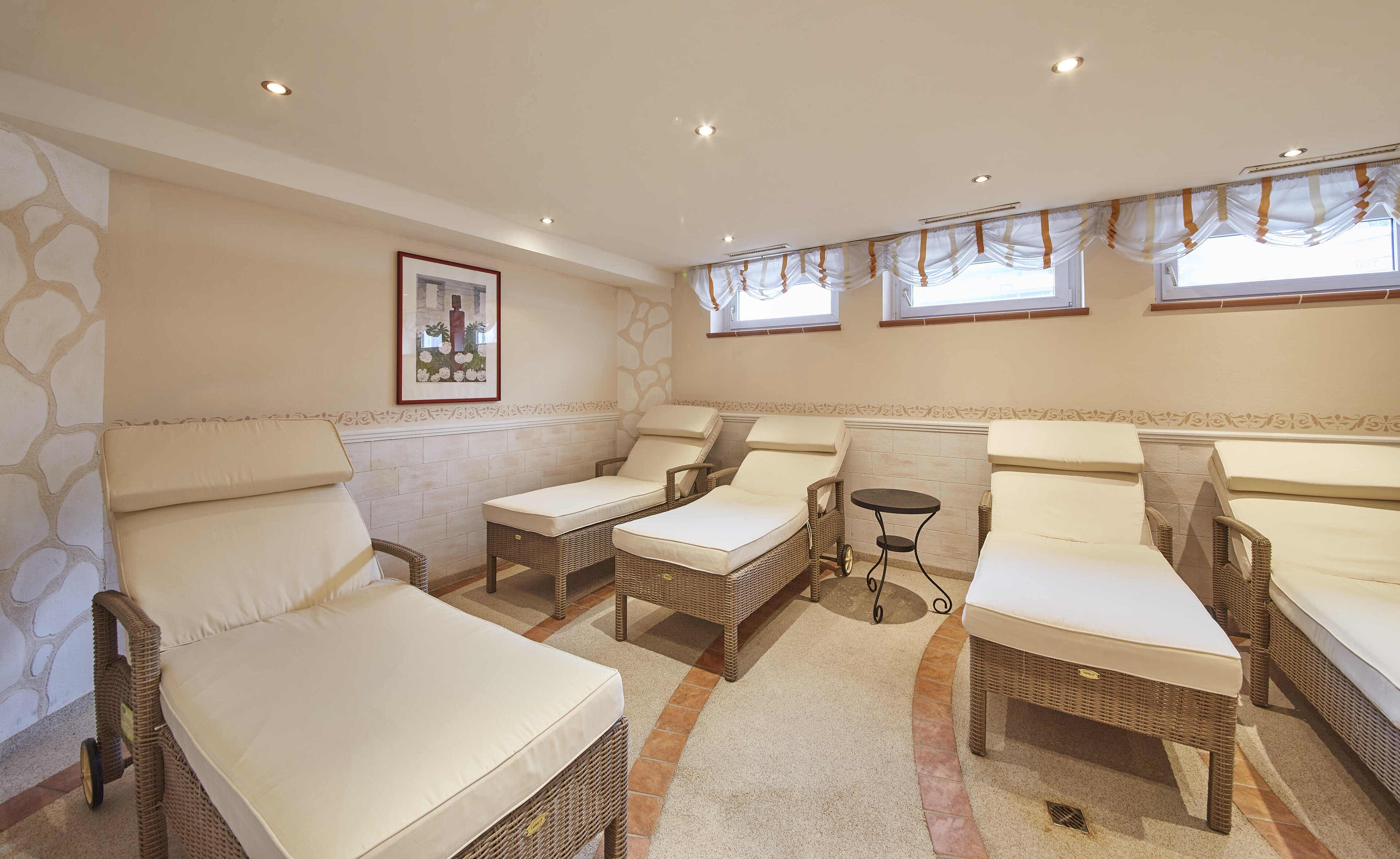 A room with wicker furniture, including two sofas and two armchairs, a small round table, and a picture on the wall.