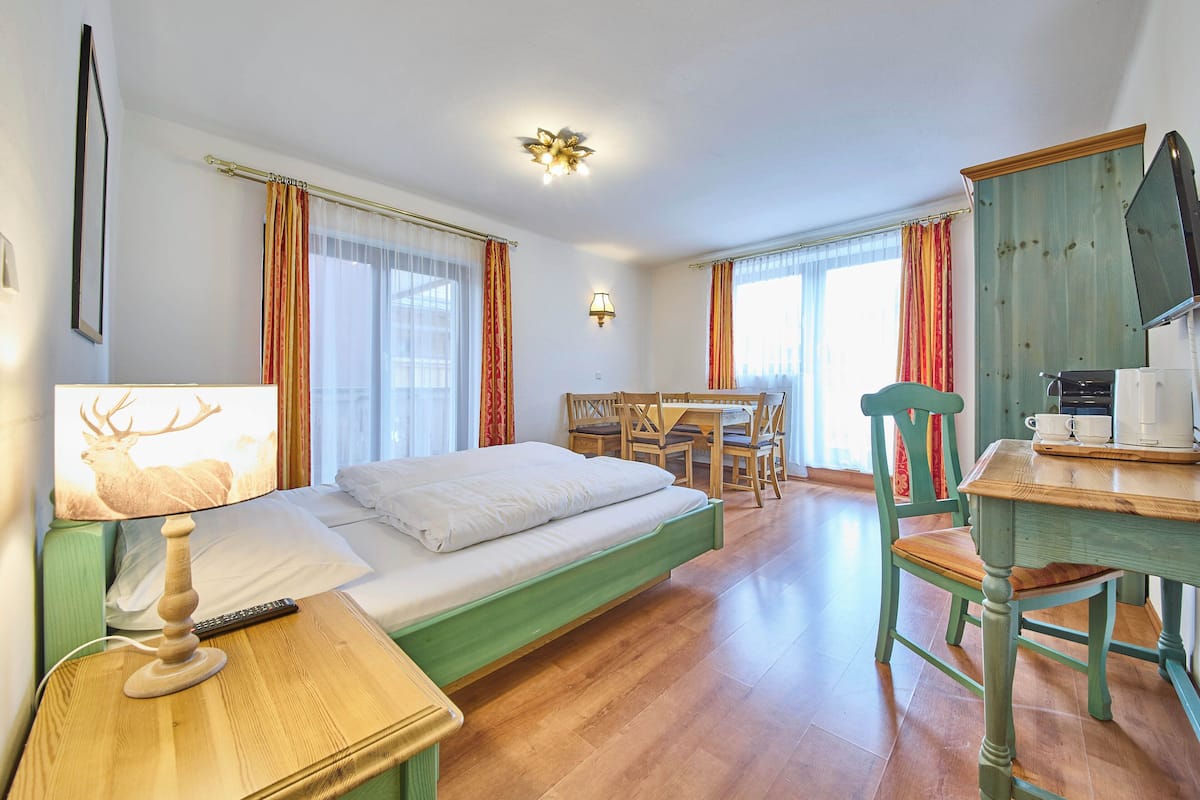 Une chambre avec un lit, un bureau et une chaise, une lampe et un téléviseur.