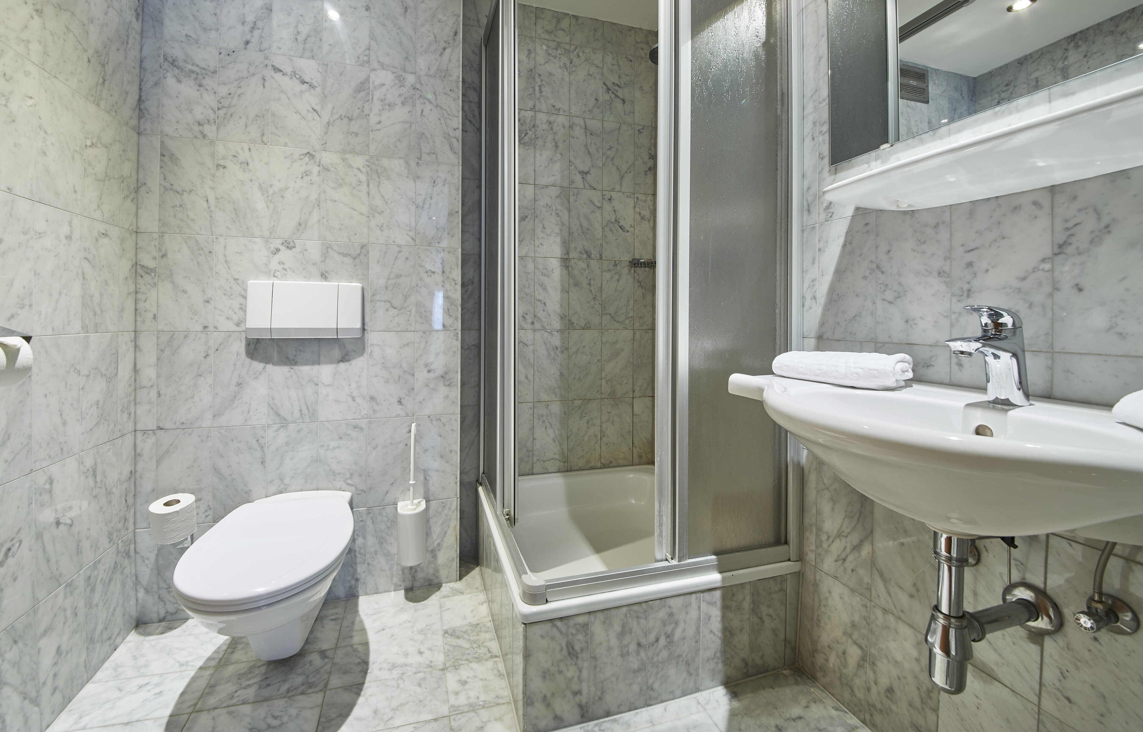Et moderne badeværelse med toilet, brusebad og vask.