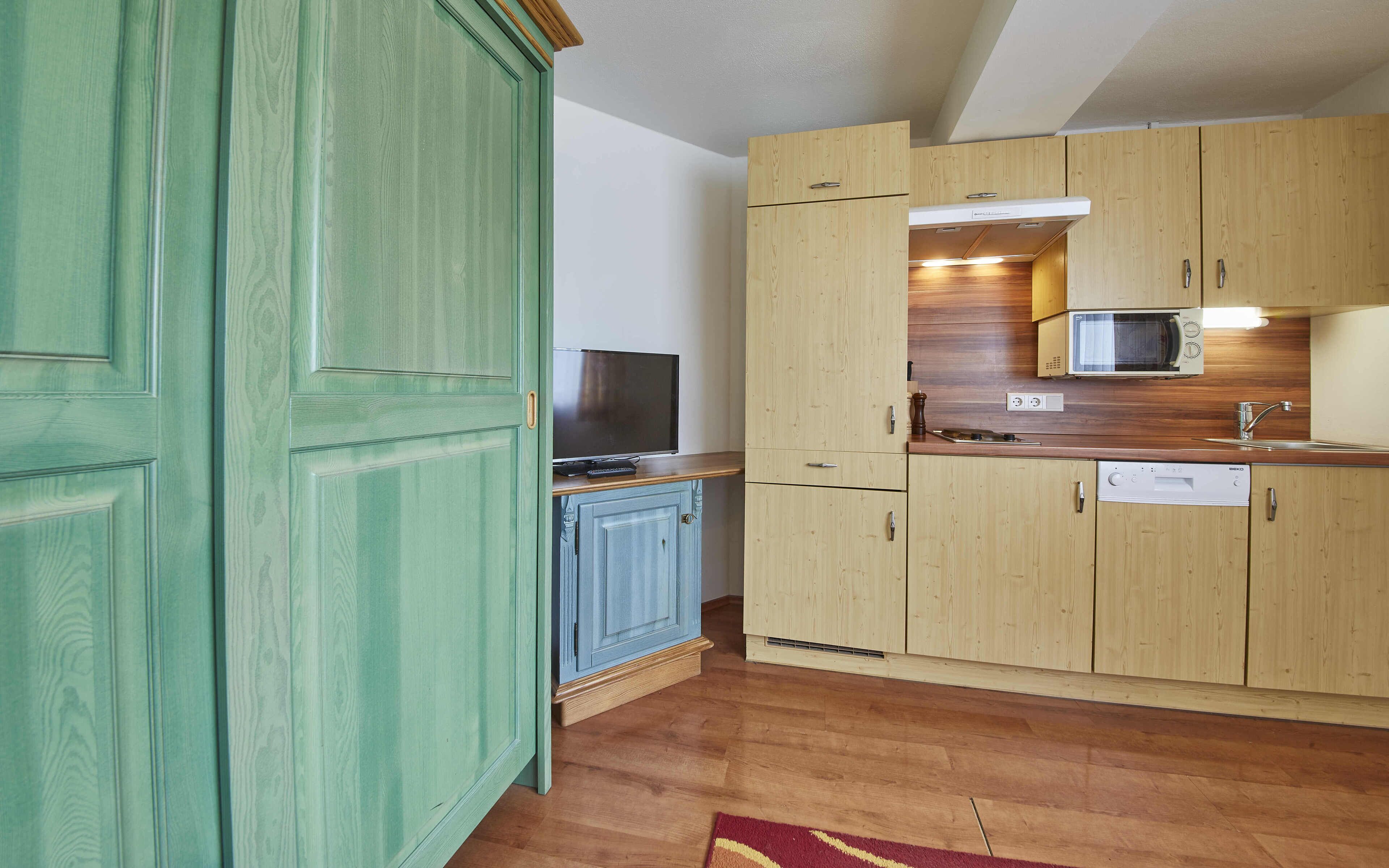Una cocina compacta con armarios de madera, un microondas y un horno empotrado.