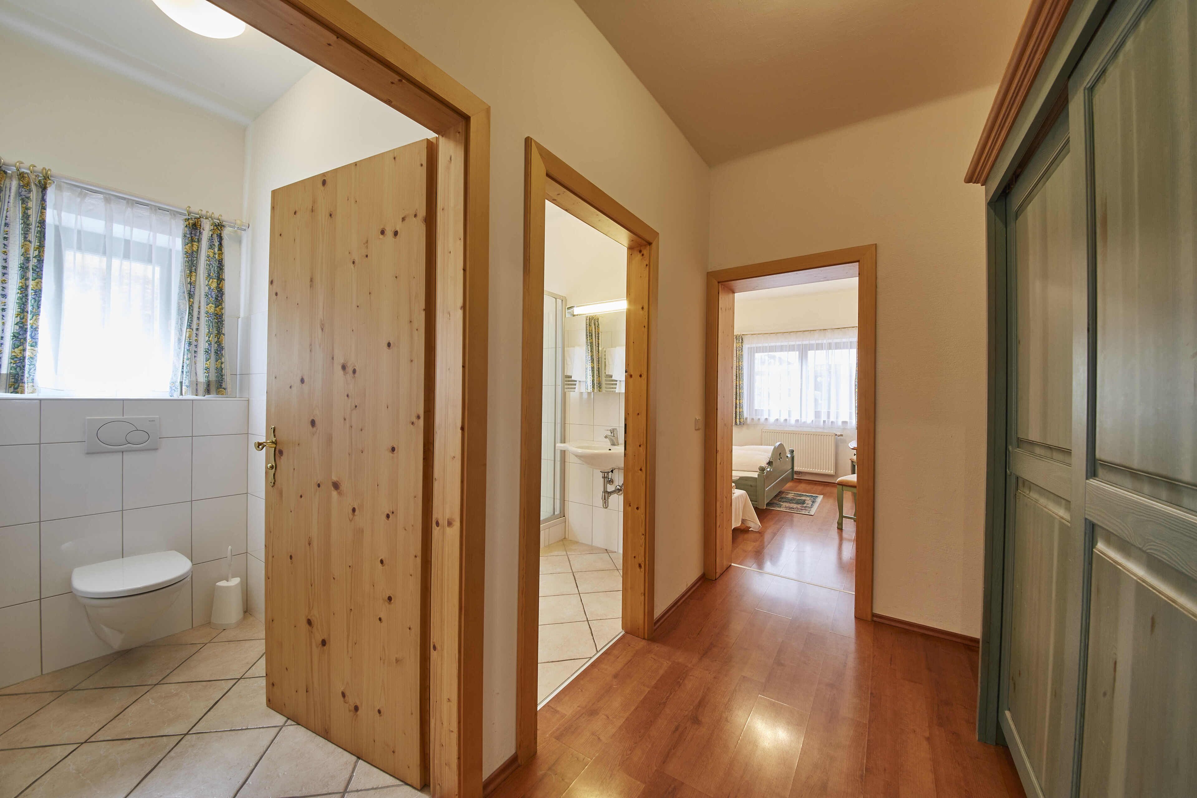 Un pasillo con puertas de madera que dan a un baño y un dormitorio.