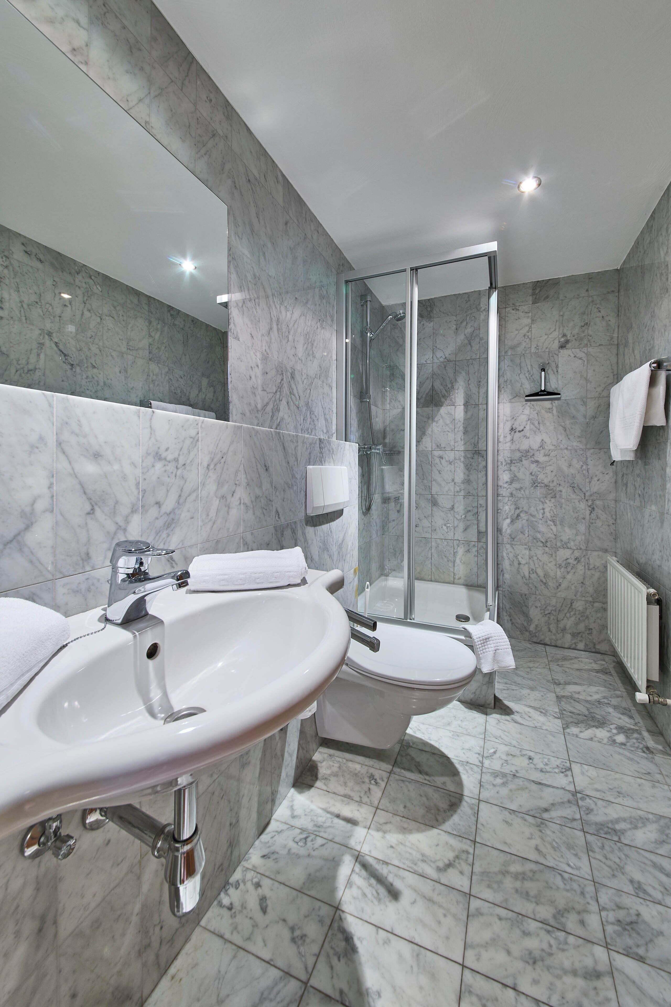 Ein modernes Badezimmer mit Marmorwaschbecken, Toilette und einer Duschkabine.
