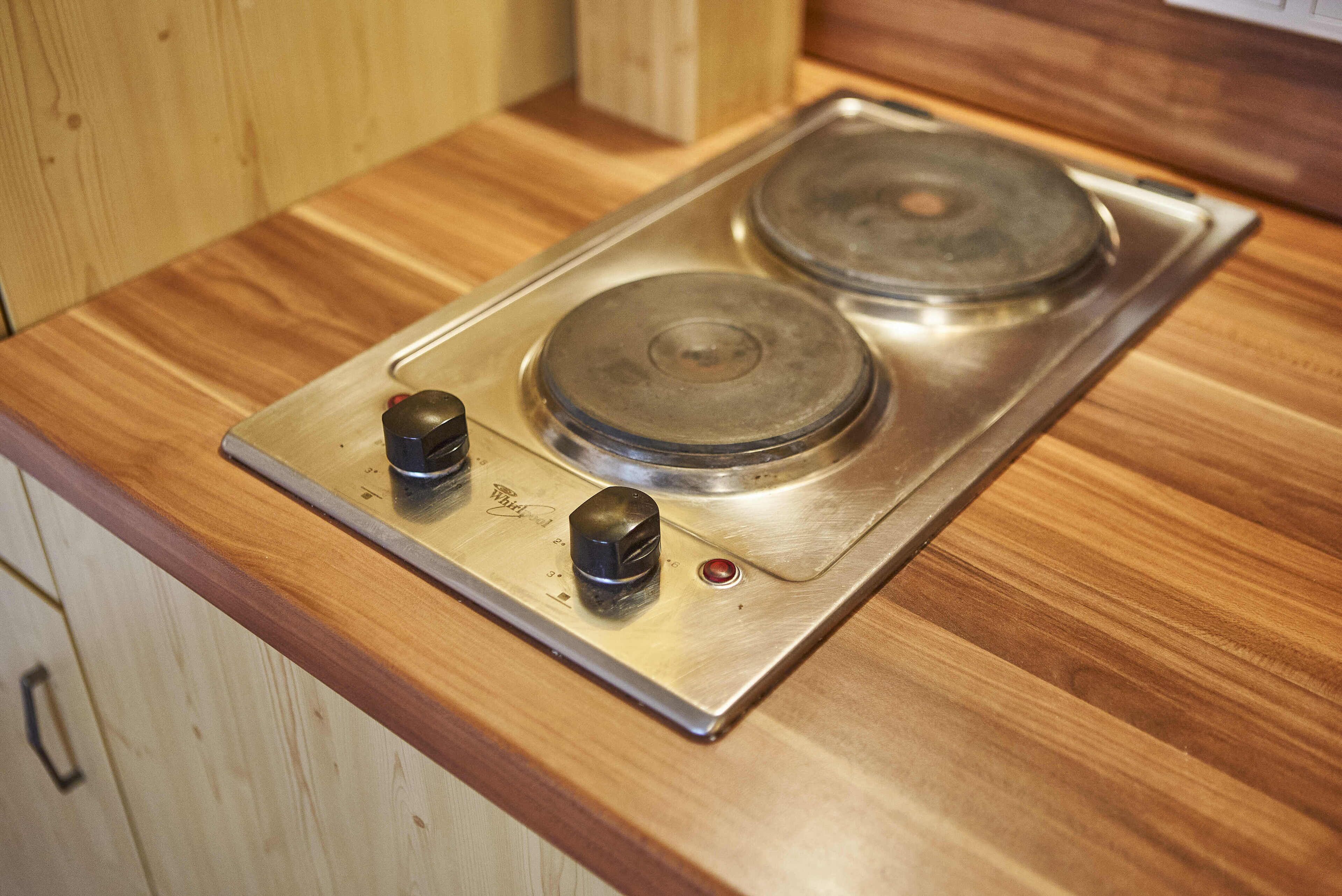 A stainless steel stove with two burners and a control knob on a wooden countertop.