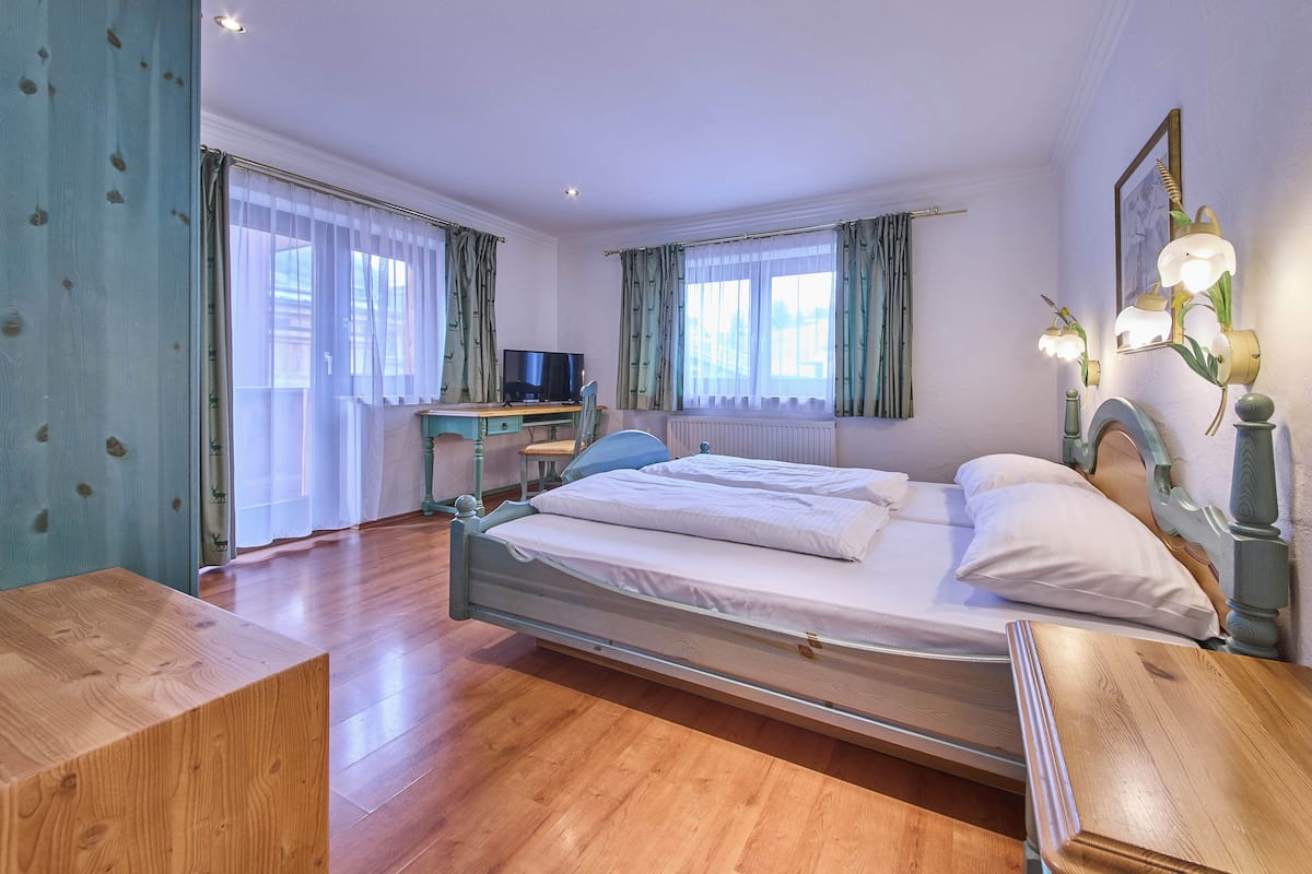 Une chambre à coucher avec un lit en bois, un bureau avec une chaise et un téléviseur.