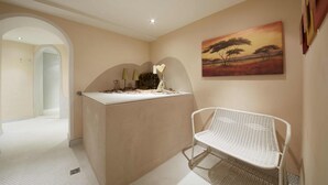 Una habitación con un banco blanco, un cuadro de un atardecer y una mesa con un adorno en forma de corazón.