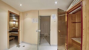 Habitación de hotel con sauna de madera, cabina de ducha de vidrio y suelo de baldosas.