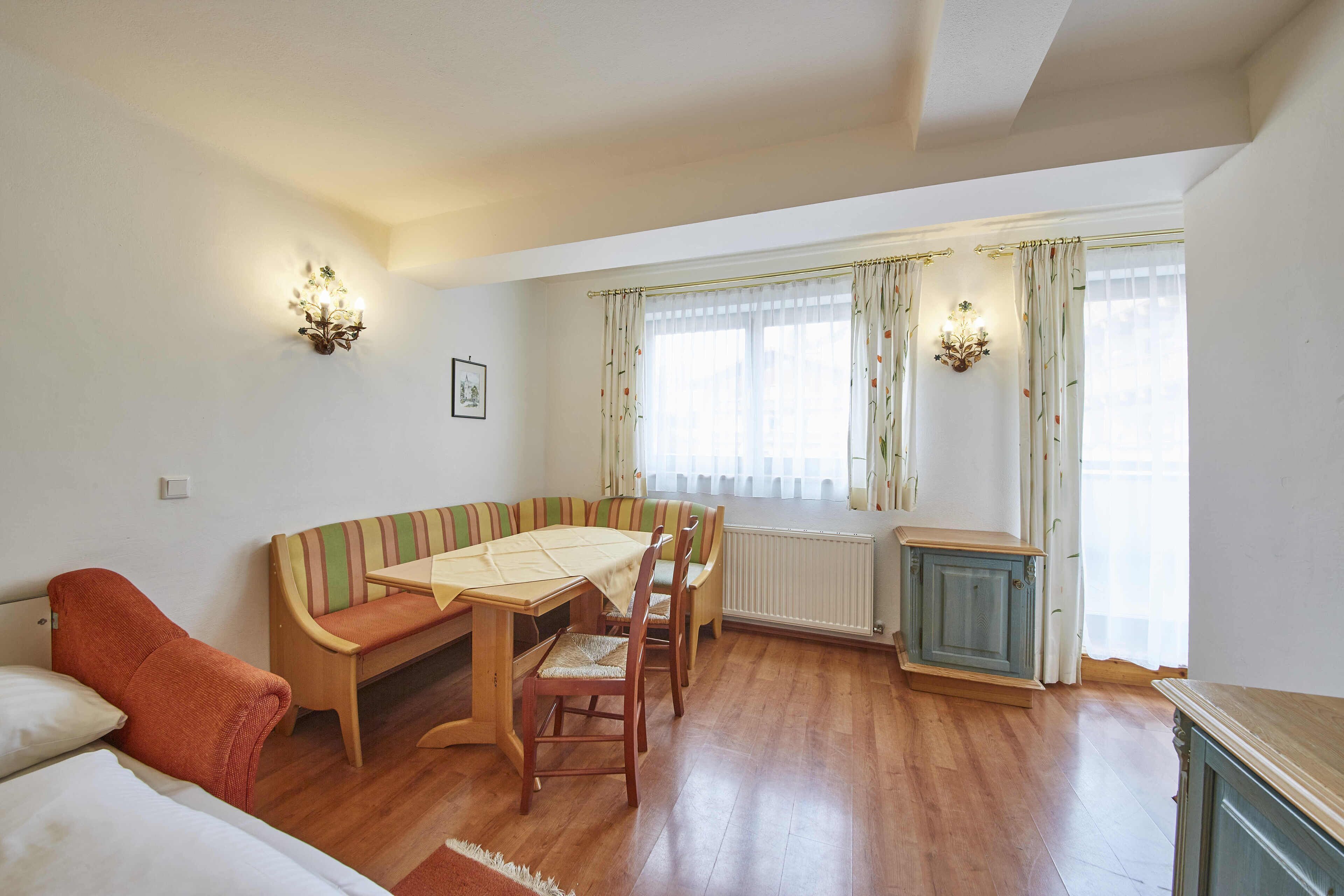 A cozy room with a wooden dining table, striped sofa, and a small cabinet.
