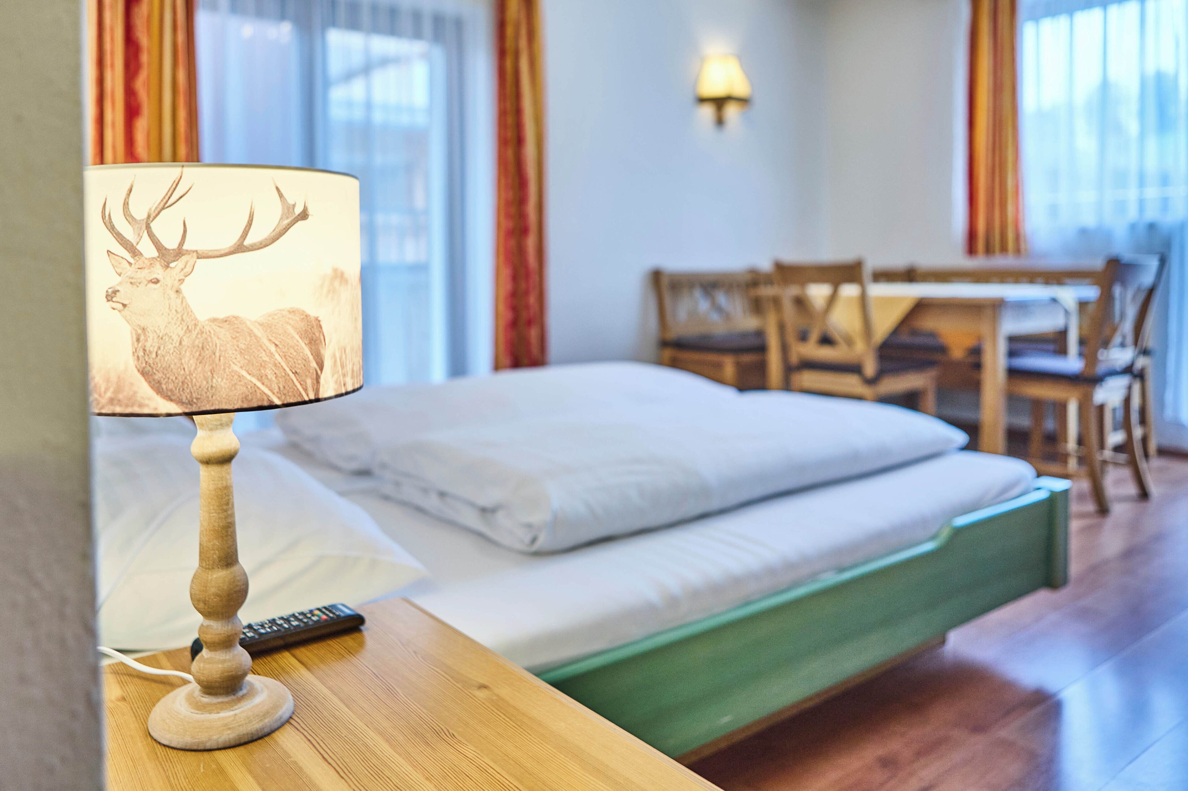 Une chambre d’hôtel avec un lit, une lampe décorée d’un motif de cerf, un bureau et des chaises.