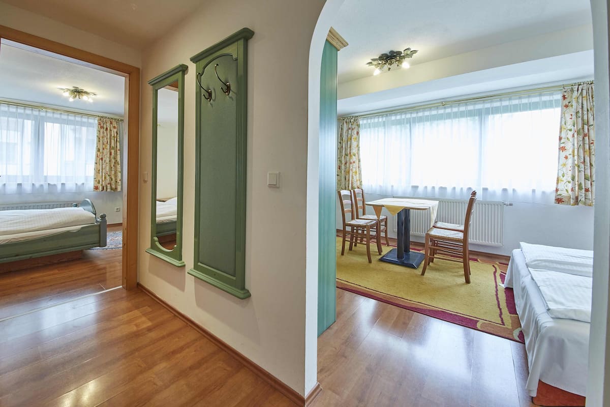 Une chambre d’hôtel avec un lit, une table à manger avec des chaises, un miroir et une fenêtre avec des rideaux.