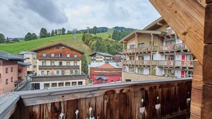 Un balcón de madera con vistas a un pueblo, incluyendo edificios y una colina al fondo.