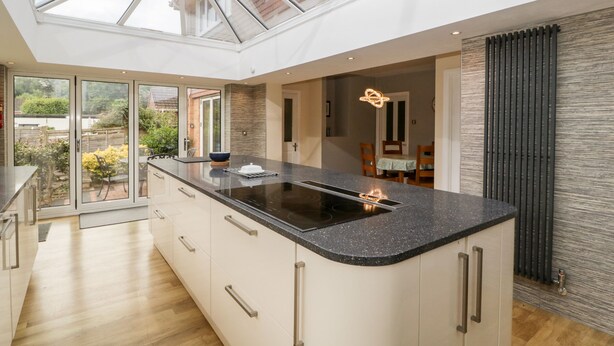 A modern kitchen with a large island, a skylight, and a view of the garden. - Sherpa (Romsey)
