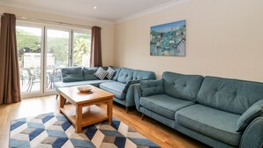 A modern living room with a sectional sofa, a wooden coffee table, and a patterned rug. - Sherpa (Romsey)